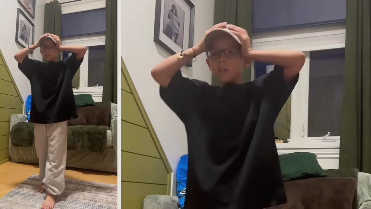 A child wearing a black Motus Gratis T-shirt, sweatpants and cap.